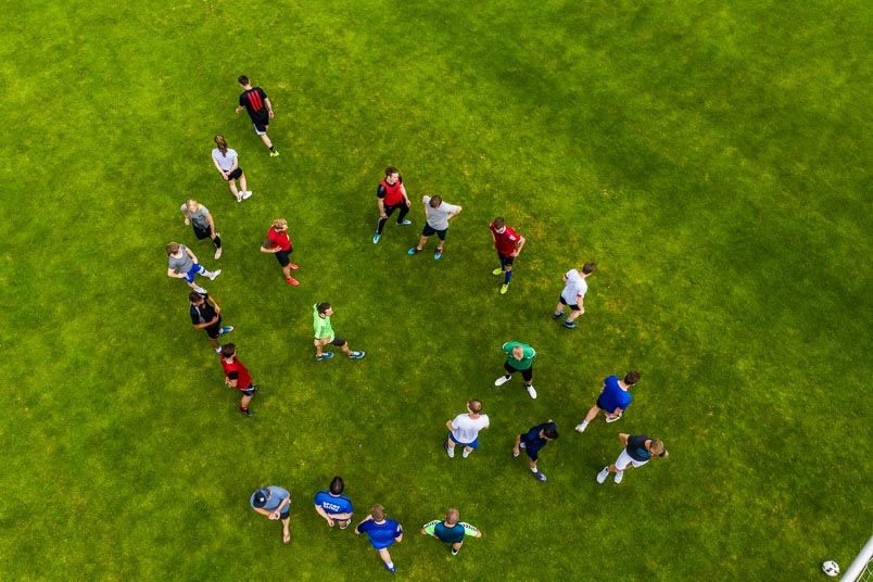 Das Foto zeigt eine Gruppe von Sportstudierenden auf einer Wiese als Luftaufnahme