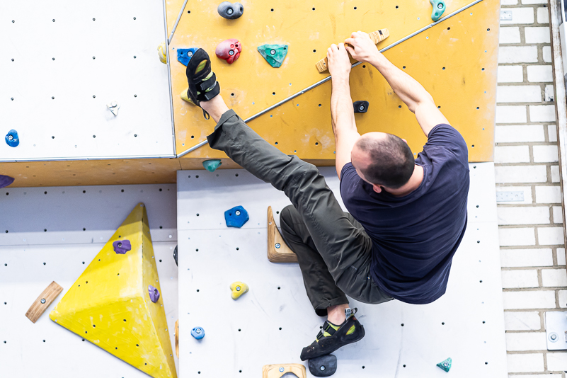 Ein Studierender klettert in einer Sporthalle eine Kletterwand hoch