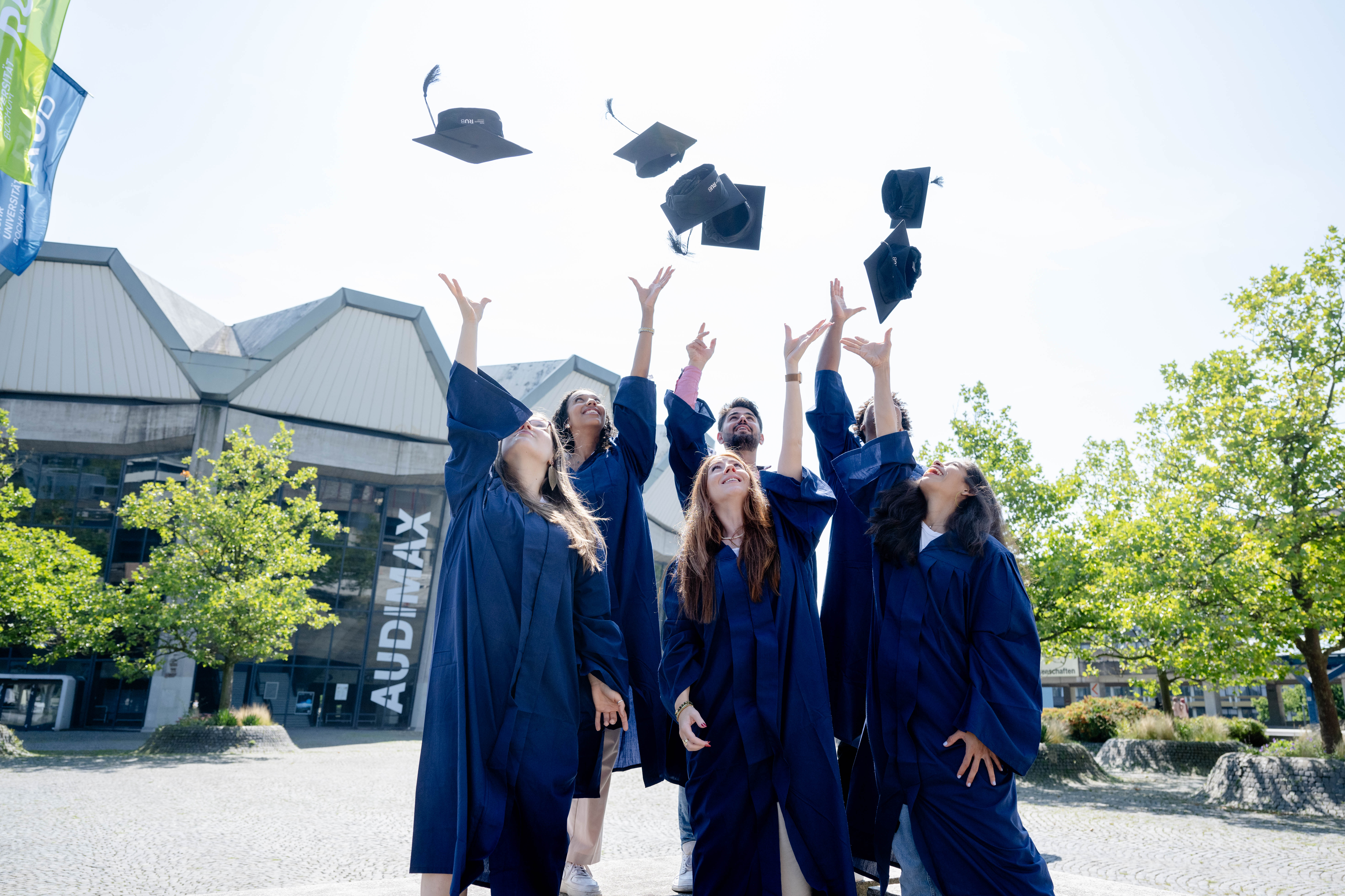 Absolventen werfen ihre Hüte in die Luft.