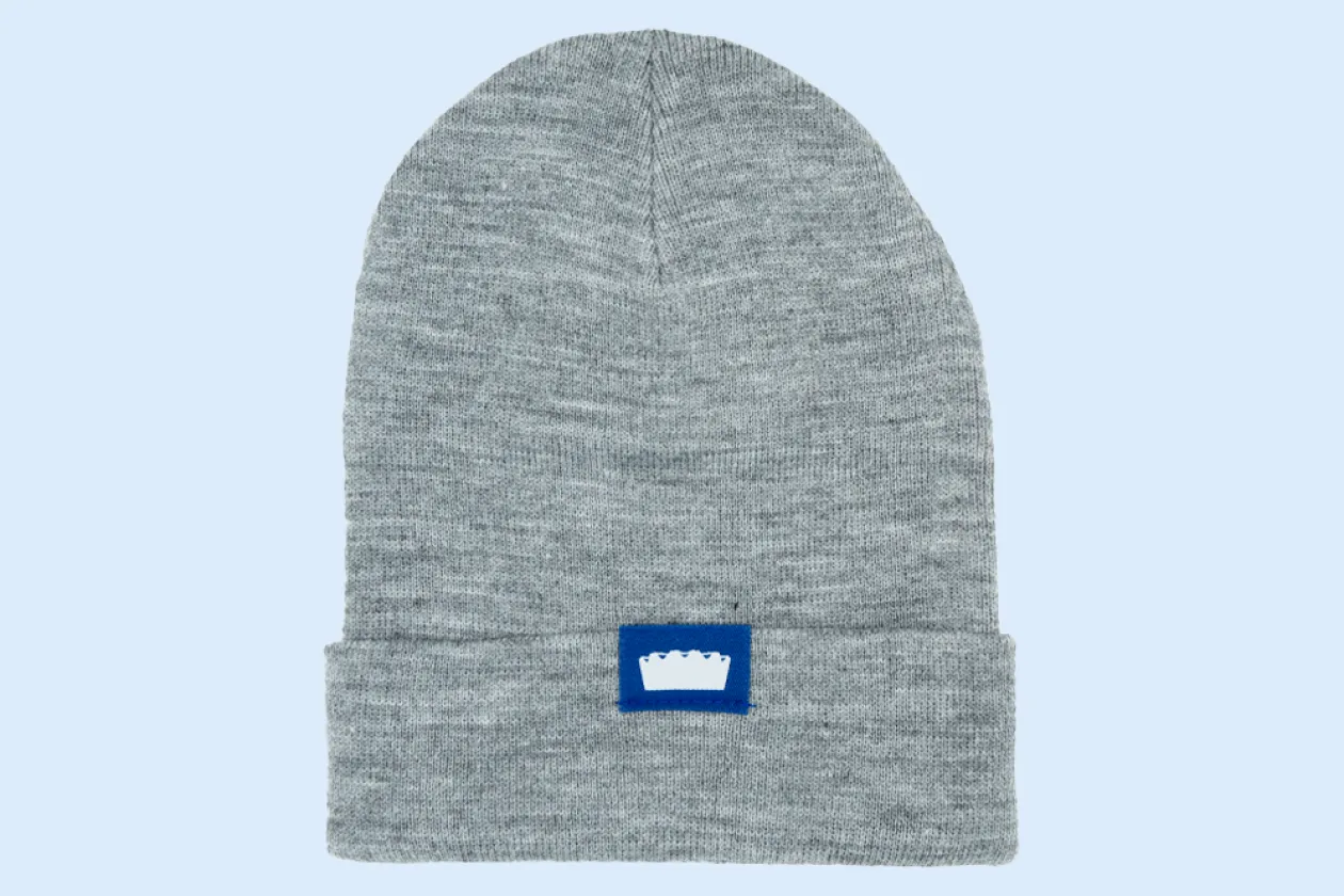 Das Bild zeigt eine graue Beanie aus dem Unishop mit Audimax-Logo