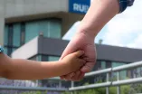 Vater hält Kind an der Hand