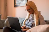 Studentin mit Laptop auf dem Sofa.