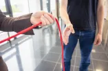 Hände geben rotes Band an