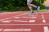 Sportler läuft über eine Tartanbahn