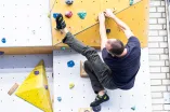 Ein Studierender klettert in einer Sporthalle eine Kletterwand hoch