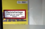Glass door with sticker "Hold-open system closes automatically in the event of fire, blocking strictly prohibited"