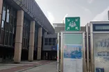 Signposting of an assembly point on the RUB campus. The icon shows four people in white on green, with four arrows pointing to them.