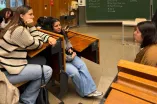 Im Hörsaal sprechen Teilnehmerinnen des Ferienakademie mit einer Mitarbeiterin der Zentralen Studienberatung