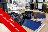 Das Foto zeigt verschiedene Artikel im Campusshop und hat einen Störer mit der Aufschrift "Sale - wir räumen unser Lager"