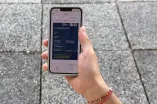 Das Bild zeigt eine Hand, die ein Handy hält, dahinter erkennt man die RUB-typischen Klapperplatten.  Auf dem Display des Handys ist ein  digitaler Studierendenausweis aufgerufen.