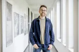 Der Projektkoordinator des Studentischen Gesundheitsmanagement, Peter Bickmann, steht vor einem hellen Flur im Uni-Gebäude SSC.