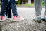 Das Foto zeigt zwei paar Schuhe von zwei Personen, die nebeneinander auf dem Forum der RUb stehen: Eine Erwachsene  mit blauen Sneakern und ein Kind mit pinken Sneakern und Klettverschlüssen