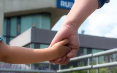 Vater hält Kind an der Hand