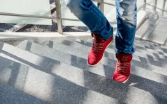 Eine Person mit roten Turnschuhen geht eine Treppe hoch.