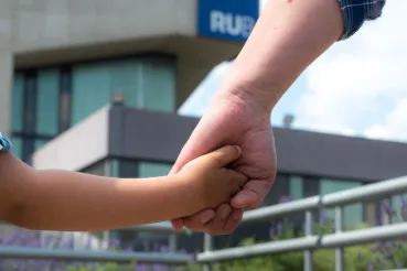 Vater hält Kind an der Hand