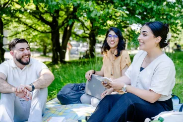 Drei Studierende auf einer Wiese