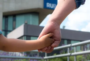 Vater hält Kind an der Hand