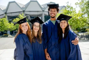 4 Alumni mit Doktorhüten und Talar auf dem Forum vor dem Audimax.