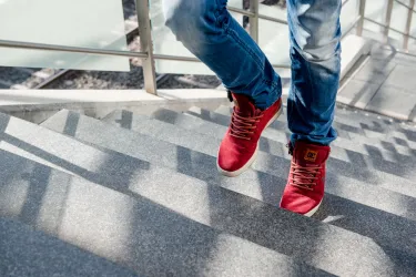 Eine Person mit roten Turnschuhen geht eine Treppe hoch.
