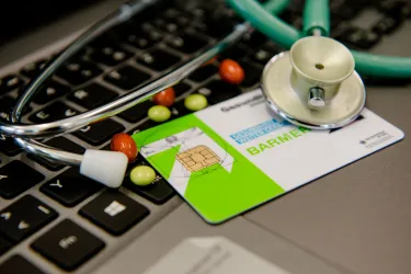 Krankenkassenkarte, Medikamente und Stethoskop auf Tastatur