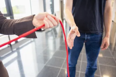 Hände geben rotes Band an