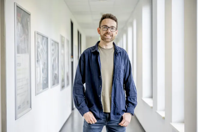 Der Projektkoordinator des Studentischen Gesundheitsmanagement, Peter Bickmann, steht vor einem hellen Flur im Uni-Gebäude SSC.