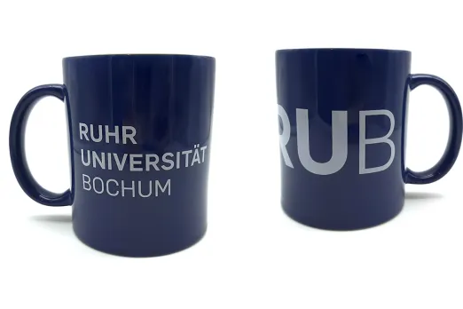 Foto: Zwei dunkelblaue Kaffeebecher, einer mit großem RUB-Logo, der andere mit dem RUB-Schriftzug