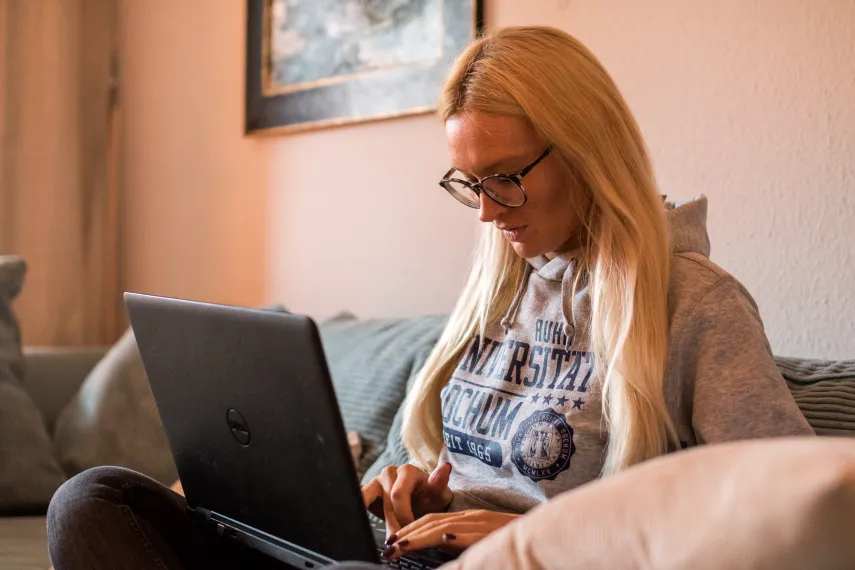 Studentin mit Laptop auf dem Sofa.
