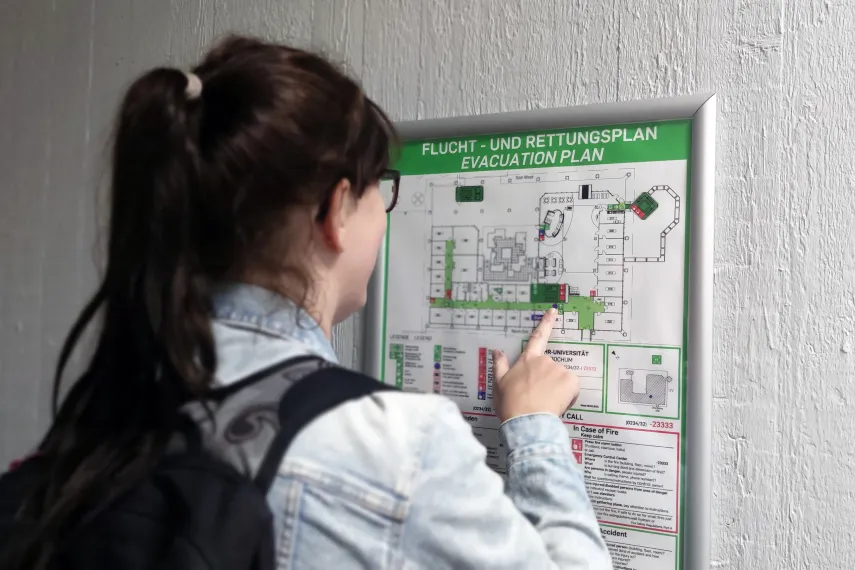 Student in front of an escape and rescue plan in a RUB building