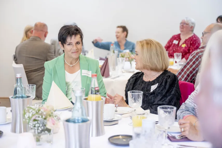 Zwei Frauen sitzen an einem Tisch mit Flaschen und Gläsern