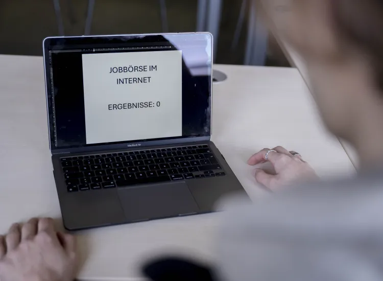 Blick über die Schulter einer Person auf einen Laptopbildschirm.