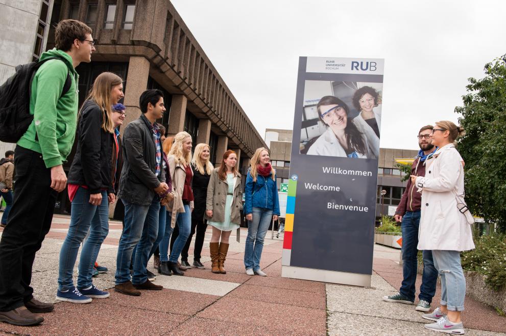 Eine Schülergruppe steht vor dem Eingangsschilder der Ruhr-Universität Bochum.