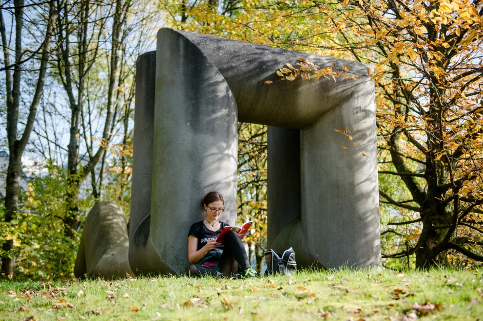 Studentin liest auf einer Herbstwiese auf dem RUB-Campus