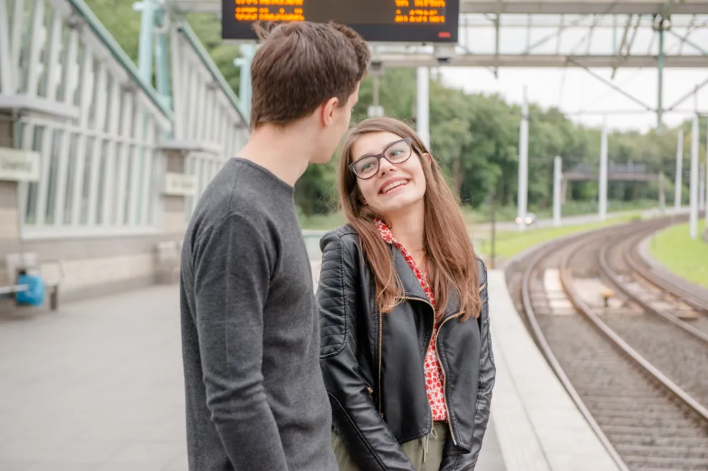 Student und Studentin am Gleis der Haltestelle Ruh-Universität.