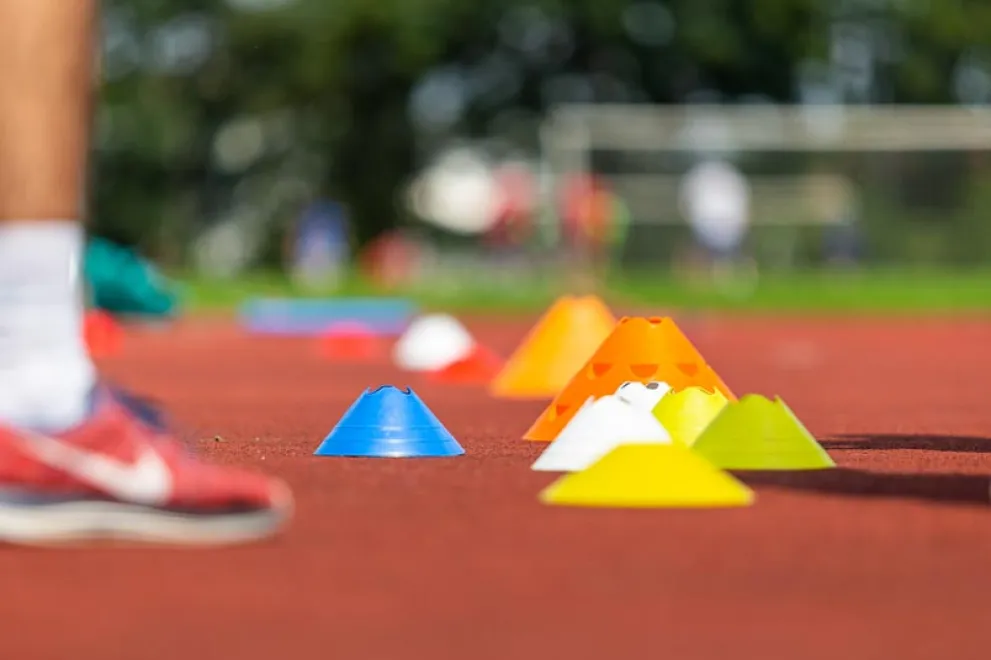 Bunte Hütchen liegen als Markierungspunkte auf einer Tartanbahn