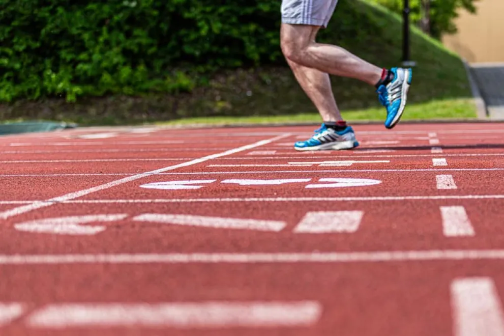 Sportler läuft über eine Tartanbahn