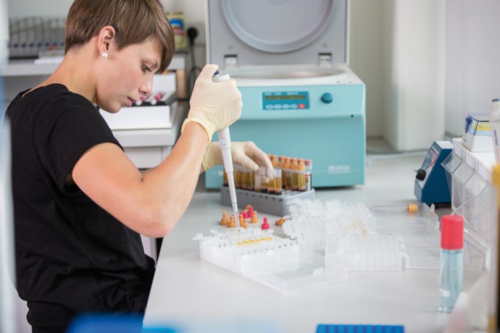 Eine junge Frau arbeitet im Labor mit einer Pipette