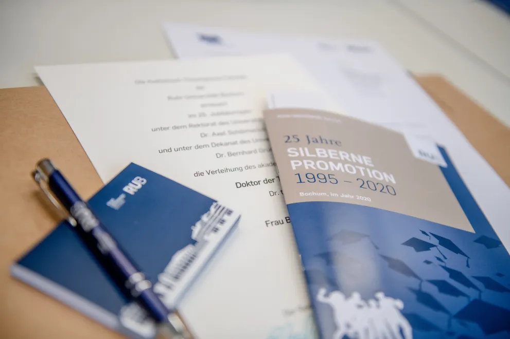 Die Silbernen Promovenden erhalten eine Jubiläumsbroschüre, ihre erneuerte Promotionsurkunde und kleine Geschenke aus dem Unishop der RUB.