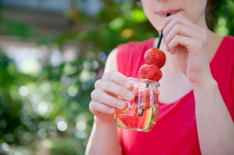 Studentin trinkt von Sommerdrink mit Erdbeeren