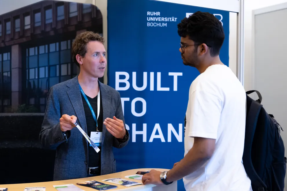 Studierender, der sich an einem Messestand beraten lässt