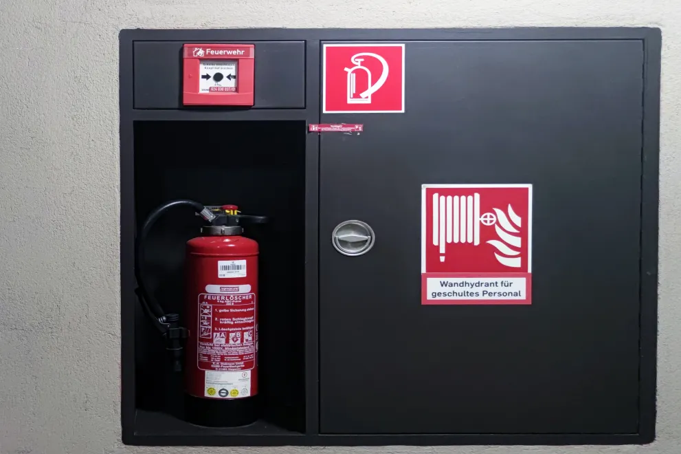 Wandhydrant, Feuerlöscher und Alarmknopf an einer Wand in einem Gebäude der RUB