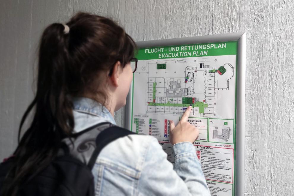 Student in front of an escape and rescue plan in a RUB building