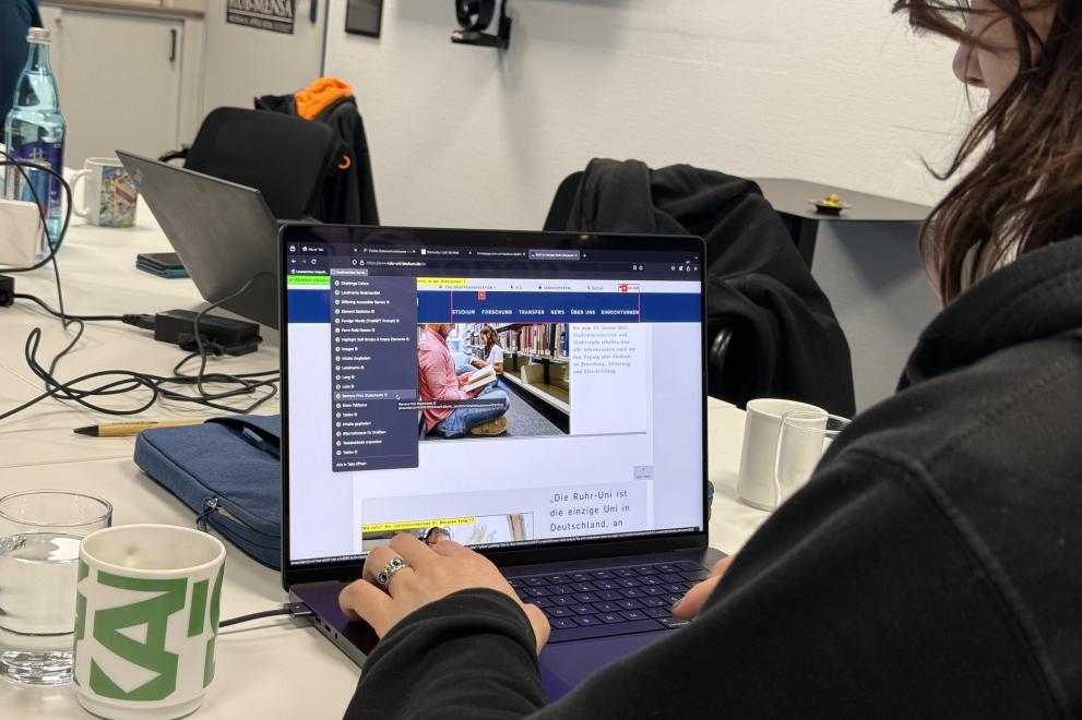 Ein Teilnehmer des Workshops "Digitale Barrieren erkennen, benennen, vermeiden" sitzt vor einem Laptop; auf dem Bildschirm ist zu sehen, wie die RUB-Homepage auf ihre digitale Barrierefreiheit hin untersucht wird.