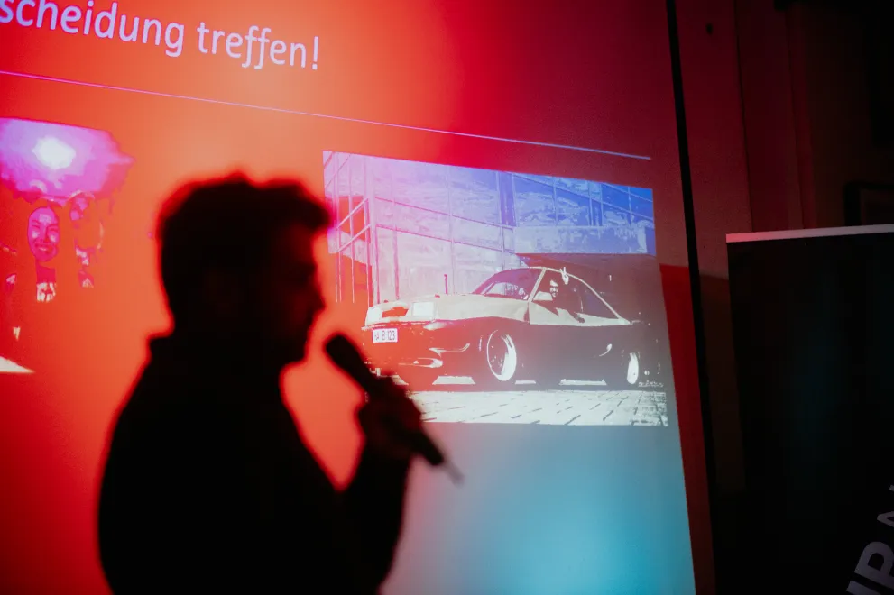 Man sieht die Silhouette einer Person, die eine Präsentation hält.