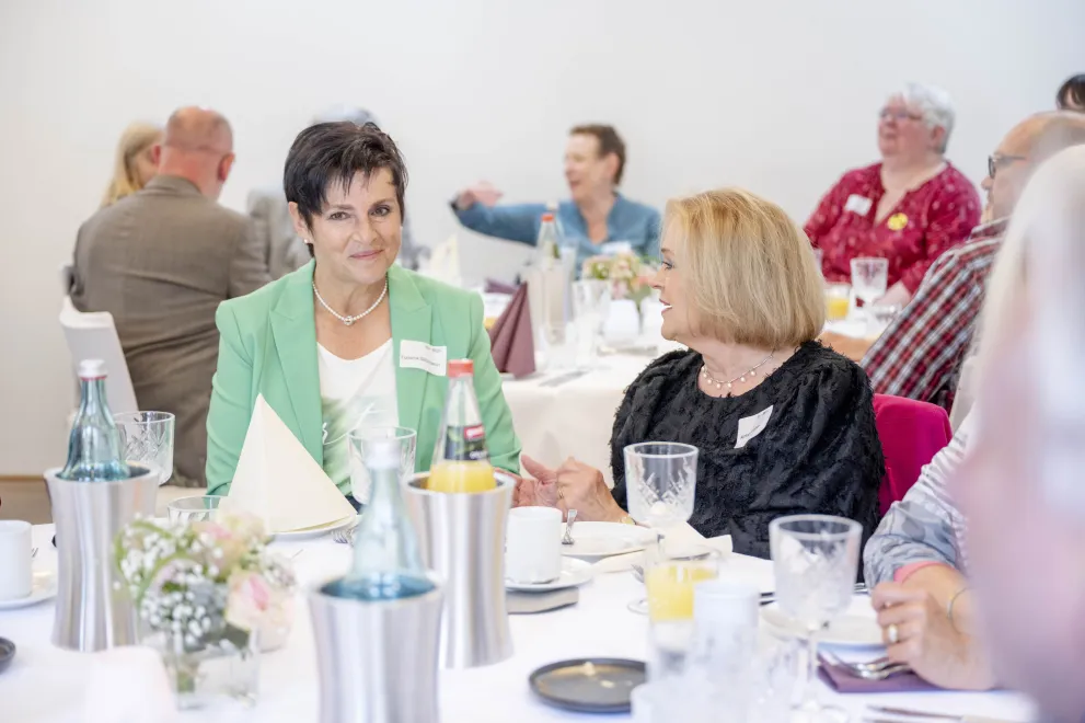 Zwei Frauen sitzen an einem Tisch mit Flaschen und Gläsern