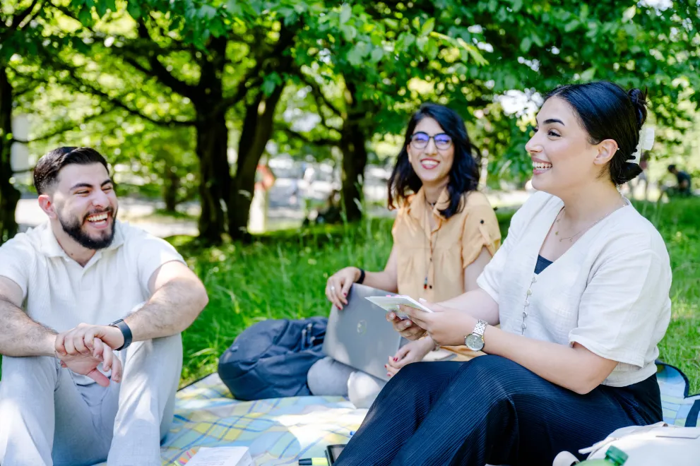 Drei Studierende auf einer Wiese