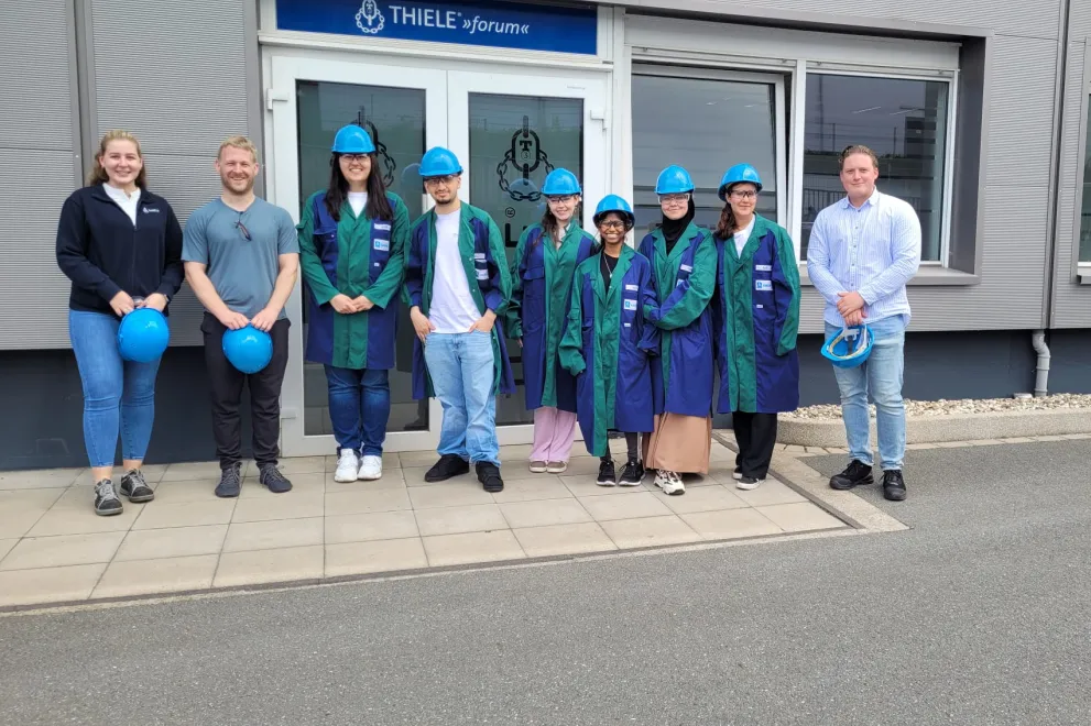 Gruppenaufnahme der Teilnehmer*innen des Sommerferienakademie mit blauen Helmen vor dem Unternehmen Thiele.