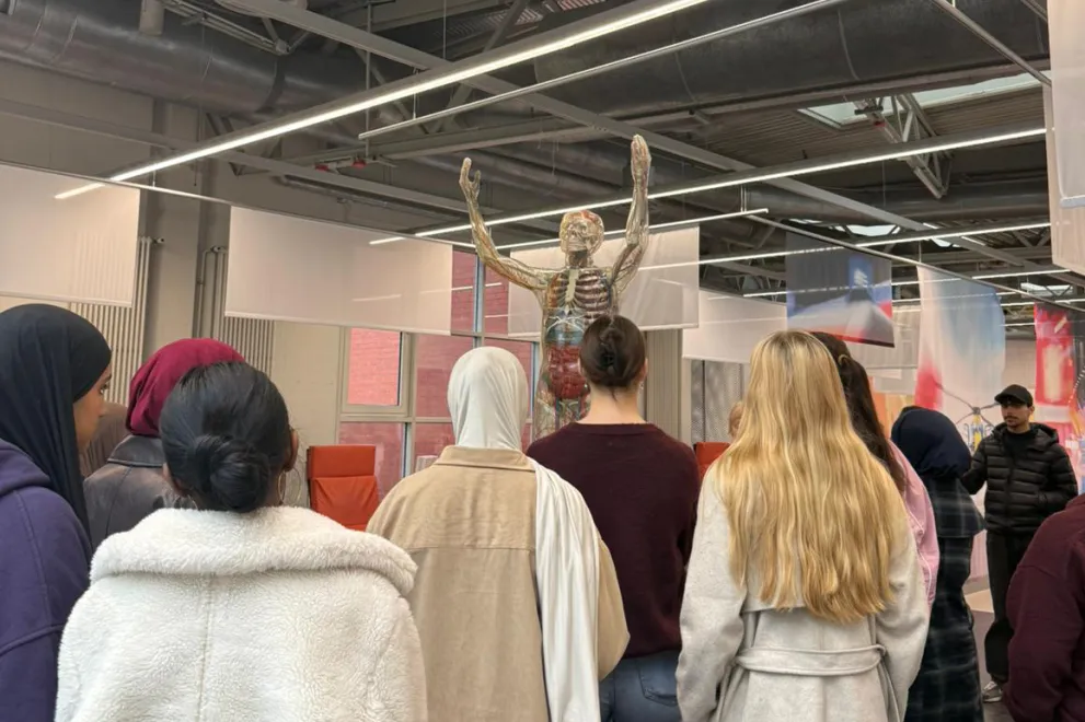 Teilnehmende der Ferienakademie stehen vor einem Modell der DASA-Ausstellung, dass Skelett, Herz-Kreislauf-System und Organe des menschlichen Körpers zeigt