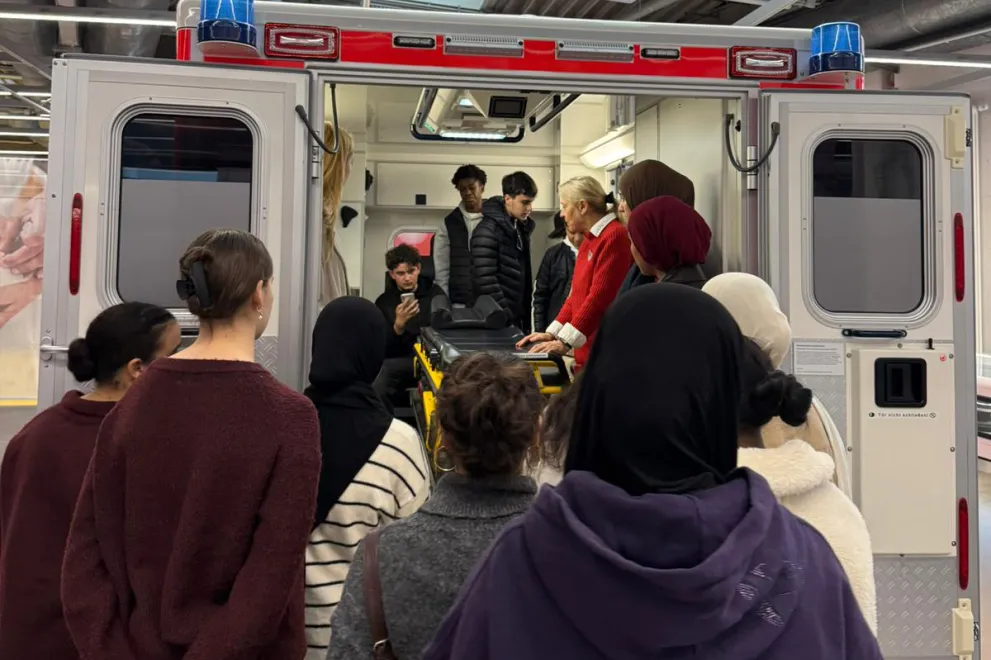 Teilnehmende der Ferienakademie sehen sich auf der DASA-Ausstellung in einem Krankenwagen um