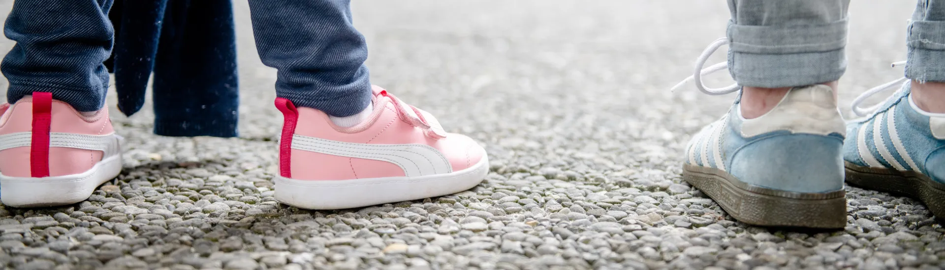 Das Foto zeigt zwei paar Schuhe von zwei Personen, die nebeneinander auf dem Forum der RUb stehen: Eine Erwachsene  mit blauen Sneakern und ein Kind mit pinken Sneakern und Klettverschlüssen